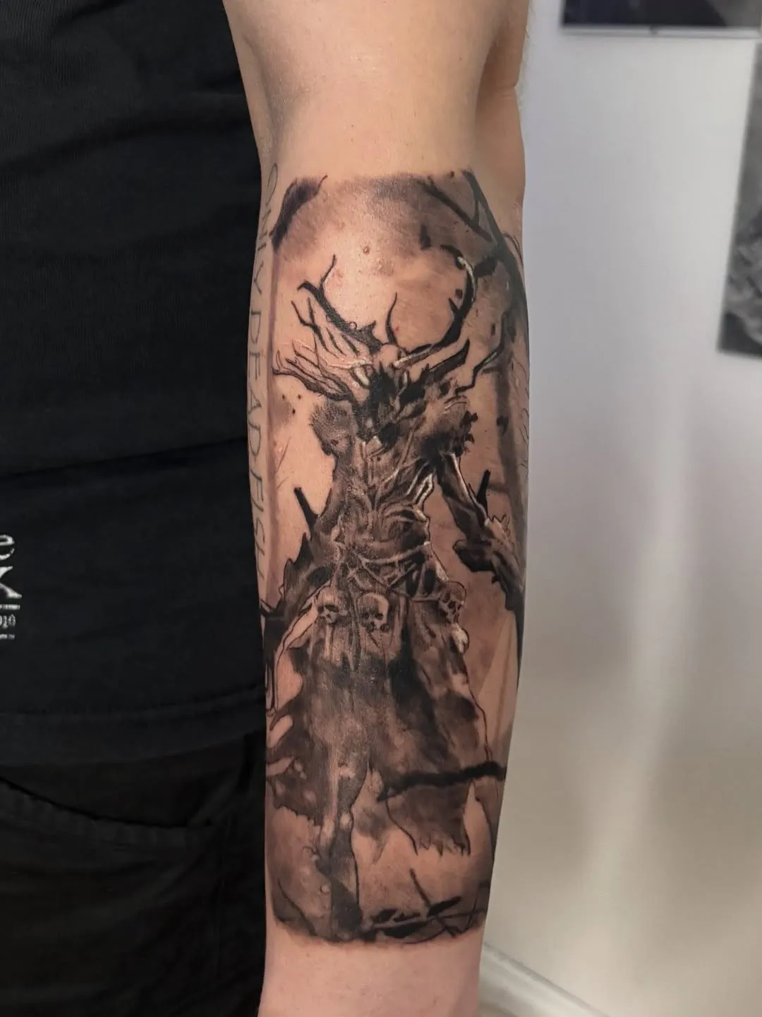 Large forearm piece — an antlered dark deity emerging from twisted bare trees, with skulls and bats in a brooding atmospheric composition.