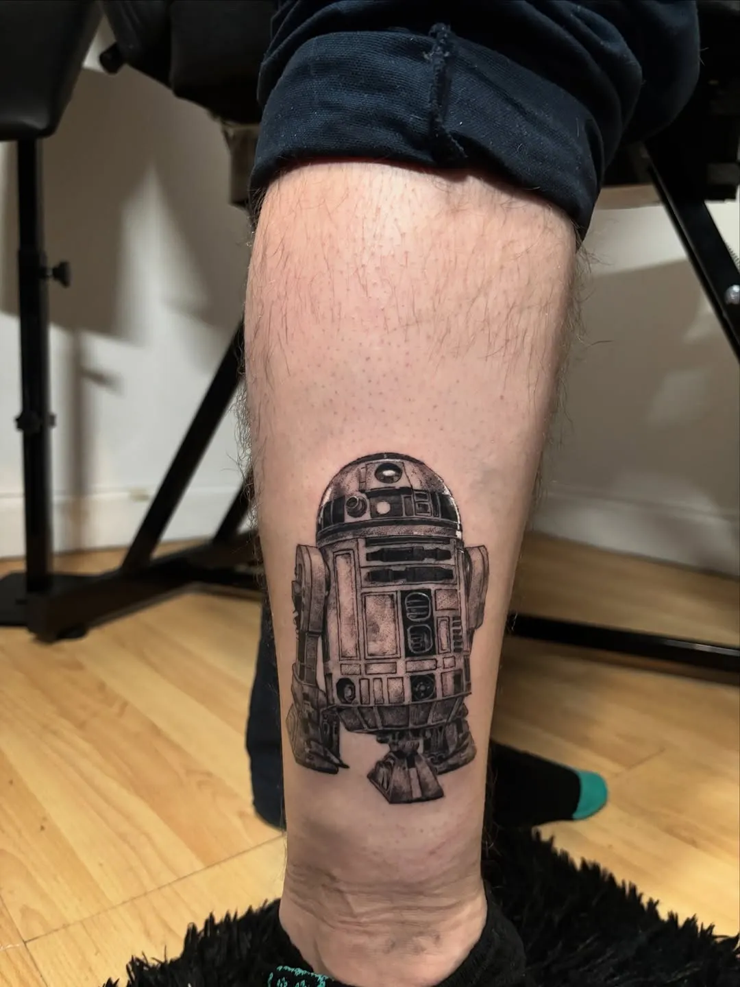 Highly detailed black & grey realism portrait of R2-D2 on the calf, capturing every panel and mechanical detail of the iconic droid.