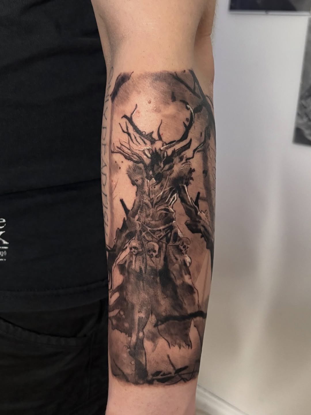 Large forearm piece — an antlered dark deity emerging from twisted bare trees, with skulls and bats in a brooding atmospheric composition.